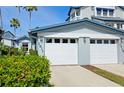 Garage doors of a two-story home featuring palm trees and lush landscaping at 1311 Siesta Bayside Dr # 1311-A, Sarasota, FL 34242