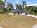 Scenic view of a modern single-story home surrounded by lush greenery and a long driveway at 2704 Gaspar Ave, North Port, FL 34288
