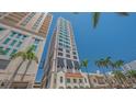 Exterior view of a high rise condo with multiple stories and balconies, framed by lush palm trees against a blue sky at 33 S Palm Ave # 1303, Sarasota, FL 34236