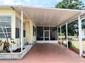 View of the home's covered carport and entrance, featuring a neatly maintained exterior and adjacent landscaping at 3318 Oakwood S Blvd, Sarasota, FL 34237