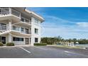 Building exterior view featuring balconies, parking, and landscaping with boats at the docks at 3320 Gulf Of Mexico Dr # 208C, Longboat Key, FL 34228
