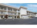 Exterior view of building showcasing balconies, parking, and a well maintained landscape at 3320 Gulf Of Mexico Dr # 208C, Longboat Key, FL 34228