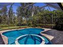 Relaxing screened-in pool and spa with a view of the green backyard and surrounding trees at 4584 Tuscana Dr, Sarasota, FL 34241