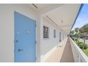 Exterior view of a condo with white siding, light blue door, and palm trees at 475 Benjamin Franklin Dr # 211, Sarasota, FL 34236