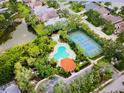 Aerial view showcases the community pool, tennis courts, and a picturesque pond surrounded by lush trees at 5091 Creekside Trl, Sarasota, FL 34243