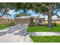 Charming single-story home featuring a manicured lawn, mature tree, and a welcoming two-car garage at 5091 Creekside Trl, Sarasota, FL 34243