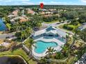 Aerial view of the community pool, clubhouse, palm trees, and surrounding lush landscaping at 6248 Donnington Ct, Sarasota, FL 34238