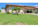 Inviting single-story home with a lush green lawn, vibrant flowerbeds, and a convenient carport at 6422 Auburn Ave, Bradenton, FL 34207