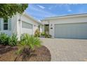 The property features a multi-car garage, verdant landscaping, and a driveway paved with pavers at 7717 Sandhill Lake Dr, Sarasota, FL 34241