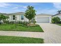 Charming home featuring a well-manicured lawn, mature landscaping, and a paved driveway leading to the garage at 7717 Sandhill Lake Dr, Sarasota, FL 34241