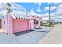 Side view of a pink house with a garage and awning, showcasing its unique charm at 8 Desoto E St, Bradenton, FL 34208