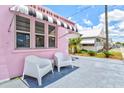 Charming home with a pink exterior, black and white awnings, and an outdoor seating area at 8 Desoto E St, Bradenton, FL 34208