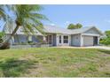 Inviting single-story home with a lush front yard, mature palm tree, attached garage, and a charming entryway with flower beds at 104 Hourglass Dr, Venice, FL 34293