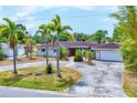Inviting single-story home featuring a pergola, red tile roof, mature landscaping, and circular driveway at 3432 Pine Valley Dr, Sarasota, FL 34239