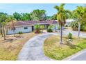 Charming single-story home with a red tile roof, circular driveway, and mature palm trees at 3432 Pine Valley Dr, Sarasota, FL 34239