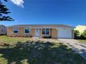 Charming single-story home with a well-manicured lawn, attached garage, and brick walkway at 354 Lasayette Ne Dr, Port Charlotte, FL 33952