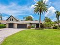 Beautiful home featuring a well-maintained lawn, brick driveway, mature palm trees, and a two-car garage at 3905 Country View Dr, Sarasota, FL 34233
