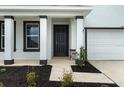 Inviting two-story home entrance featuring dark trim, two-car garage, a covered porch, and fresh landscaping at 4015 Quiet Rain Ct, Palmetto, FL 34221