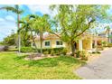 Landscaped exterior view of a yellow villa with a red tile roof and lush green lawn at 4840 Gulf Of Mexico Dr # Villa 15, Longboat Key, FL 34228