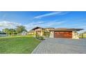 A beautifully landscaped home featuring a paver driveway and lush green lawn at 5500 Merrimac Dr, Sarasota, FL 34231
