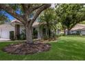 Charming home featuring a two-car garage, red tile roof, and mature trees at 5712 Garden Lakes Dr, Bradenton, FL 34203