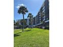 Exterior shot of a white condo building with palm trees and well-maintained lawn at 5855 Midnight Pass Rd # 621, Sarasota, FL 34242