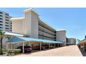 Exterior shot of the condo building showing covered parking and multiple floors of balconies with beach access at 5916 Midnight Pass Rd # 404, Sarasota, FL 34242