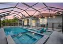 A screened-in pool and spa area with clear blue water and lounge chairs at dusk at 7705 55Th E St, Ellenton, FL 34222
