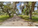 Charming single-story home with a long driveway, lush lawn, and mature trees draped with Spanish moss at 1108 64Th Street E Ct, Bradenton, FL 34208