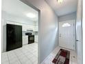 Hallway view leading to a bright kitchen equipped with modern, black appliances and tile flooring at 11717 Wesson E Cir, Tampa, FL 33618