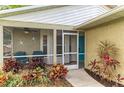 Inviting screened porch with comfortable seating, decorative starfish, and a view of a colorful front garden and a turquoise door at 4115 2Nd Nw Ave, Bradenton, FL 34209