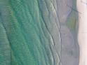 Gorgeous aerial view of crystal-clear ocean waves meeting the pristine sandy beach at 5681 Midnight Pass Rd # 104, Sarasota, FL 34242