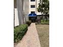 Inviting condo building entrance with a brick walkway, manicured landscaping, and a blue awning for convenient access at 6124 43Rd W St # 104A, Bradenton, FL 34210