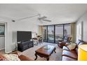 Bright living room featuring a ceiling fan, TV, leather couches, and a balcony overlooking the beach at 6480 Midnight Pass Rd # 311, Sarasota, FL 34242