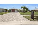 Charming single-story home featuring a well-manicured lawn, mature palm trees, and a paver driveway at 6841 Roxbury Dr, Sarasota, FL 34231