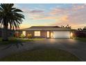 Charming home with a well-manicured lawn, palm tree, and a driveway leading to an attached two-car garage at 710 Beverly Rd, Venice, FL 34293
