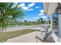 Relaxing front porch view overlooking a serene street and canal, offering a peaceful setting with tropical landscaping at 714 N Waterway Dr, Venice, FL 34285