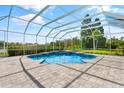 Screened pool area with a uniquely shaped pool and hot tub surrounded by lush landscaping at 7832 Panther Ridge Trl, Bradenton, FL 34202