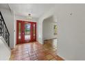 Inviting foyer featuring a red front door, terra cotta floors, and arched doorway at 8255 Longbay Blvd, Sarasota, FL 34243