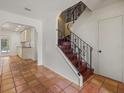 Hallway featuring terra cotta floors, staircase with iron railing, and access to other rooms at 8255 Longbay Blvd, Sarasota, FL 34243