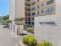 View of the property's sign at Lido Towers surrounded by lush, mature landscaping at 1001 Benjamin Franklin Dr # 106, Sarasota, FL 34236