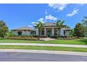 Home exterior showcasing a well-maintained lawn, vibrant flowerbeds, and a charming entrance with stately columns at 11807 Rive Isle Run, Parrish, FL 34219
