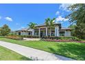 Beautiful home exterior featuring manicured landscaping, palm trees, and elegant architectural details under a bright blue sky at 11807 Rive Isle Run, Parrish, FL 34219