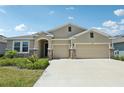 Charming single-story home with a two-car garage and stone accents under a bright blue sky at 17536 Cantarina Cv, Bradenton, FL 34211