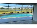 Sparkling in-ground swimming pool with a screened enclosure and a serene lake view beyond at 2178 Calcutta Rd, Punta Gorda, FL 33983