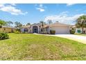 Beautifully landscaped single-story home with a two-car garage, lush green lawn, and a charming screened entryway at 251 Broadmoor Ln, Rotonda West, FL 33947