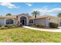 Well-maintained home featuring a screened entryway, manicured landscaping, and a paved walkway leading to the front door at 251 Broadmoor Ln, Rotonda West, FL 33947