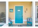 Bright turquoise front door with coastal decorations and seating on the screened porch at 2801 Dalhart Ave, North Port, FL 34286