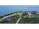 Stunning aerial view of the condo complex surrounded by lush landscaping, a golf course and a bay at 3070 Grand Bay Blvd # 644, Longboat Key, FL 34228