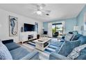 Cozy living room in a blue color scheme with a ceiling fan, artwork, sofa, chairs, and access to a balcony at 3703 5Th Ave # 3, Holmes Beach, FL 34217